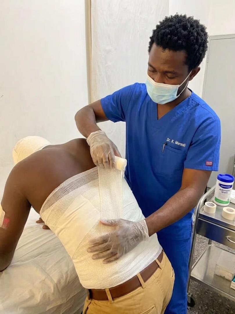 A practitioner securing an external dressing around the lower back
